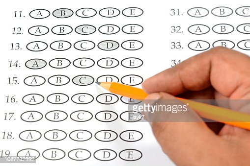 Student filling a multiple choice exam paper with pencil.